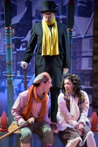 Chris Dinolfo (Tiny Tim) and Brittany Martz (Charlotte) make plans to play a trick on Scrooge  (Conrad Feininger). Photo by Bruce Douglas. 