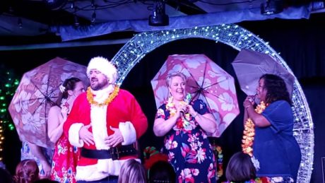 Joey Olson, backed by Katie Pond, Kat Brais, and Lisa Alford, sings "Traveling Man" in StageCoach Theatre Company's 'Santa's Funky Hawaiian Christmas Cabaret.' Photo by Laura Mills.